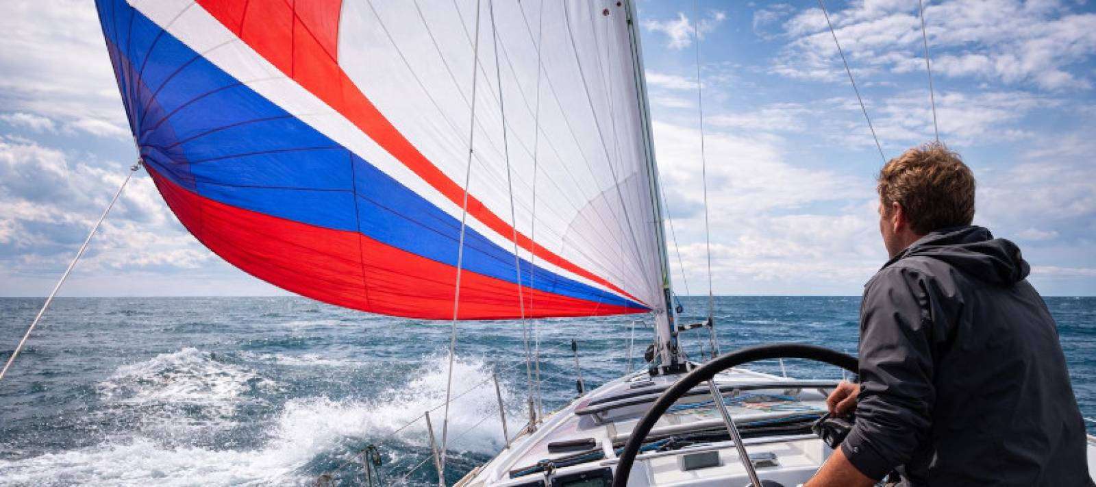 velista al timone con spinnaker colorato